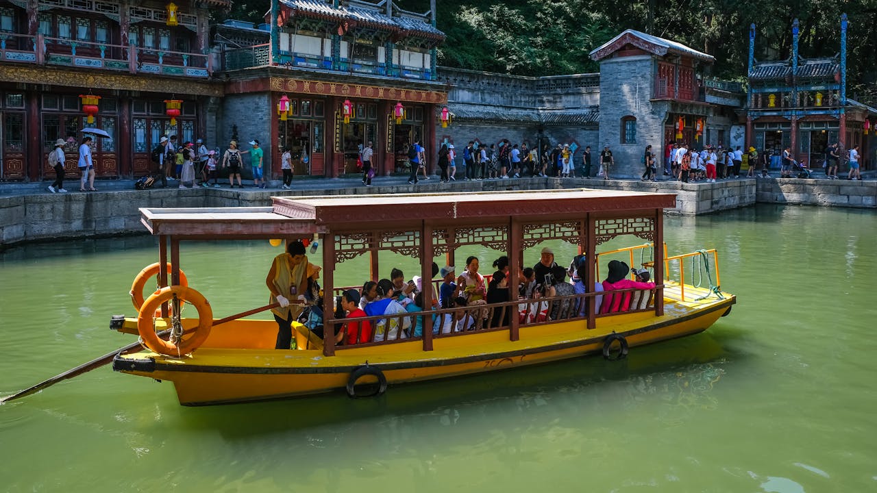 Tourists enjoy a scenic boat ride on a canal in Beijing, China, showcasing traditional architecture.